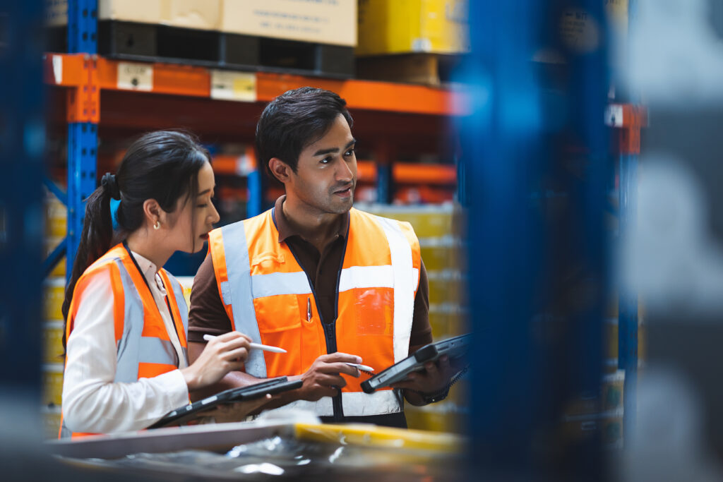 Warehouse worker and manager checks stock and inventory with using digital tablet computer in the retail warehouse full of shelves with goods. Working in logistics, Distribution center.